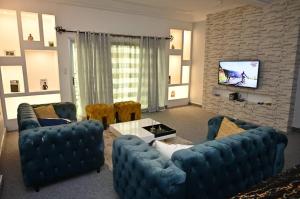 ein Wohnzimmer mit blauen Sofas und einem TV in der Unterkunft Appartement cosy gold bonapriso in Douala