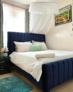 a bed with a blue headboard in a bedroom at Comfy 1br Milimani in Kisumu