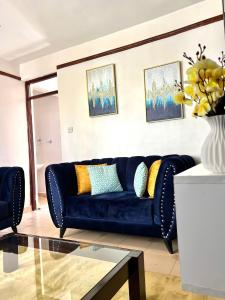 a living room with a blue couch and a glass table at Comfy 1br Milimani in Kisumu