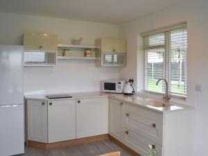 a kitchen with white cabinets and a sink at Acres View in Hoveringham