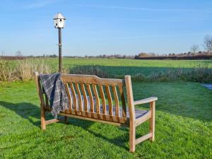 een houten bank in het gras naast een lichtpaal bij Acres View in Hoveringham