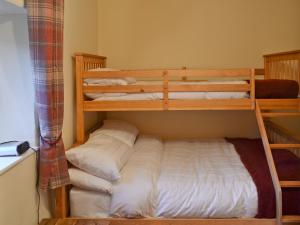 a bedroom with two bunk beds with white sheets at Coal Miners Cottage in New Mills