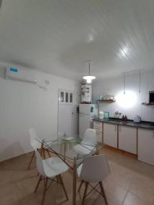 a kitchen with a glass table and white chairs at Departamento para dos personas en Monte Hermoso. in Monte Hermoso