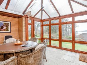 a conservatory with a table and chairs and windows at Ard Taigh in Stron-fearnan