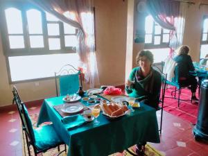 Maison d'Hôtes Ghalil في ورززات: امرأة تجلس على طاولة مع طبق من الطعام