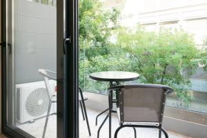 einen Tisch und Stühle auf einem Balkon mit Fenster in der Unterkunft Voda Luxury Residence #102 in Athen