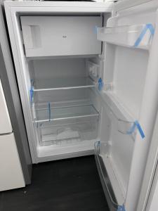 un frigorifero vuoto con la porta aperta con nastro blu di Private room and ensuite Chorlton a Manchester