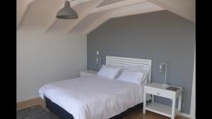 1 dormitorio con cama blanca y mesita de noche en Brenton Ocean view, en Brenton-on-Sea