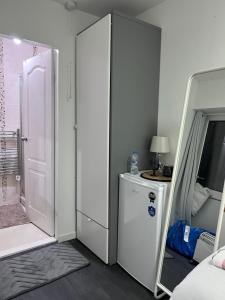 Private room and ensuite Chorlton في مانشستر: غرفة بثلاجة بيضاء وغسالة ملابس