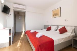 - une chambre avec un grand lit blanc et une couverture rouge dans l'établissement Boarding House Lucija, à Kostrena