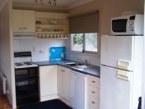 a small kitchen with a sink and a refrigerator at Pebble Shack in Coles Bay