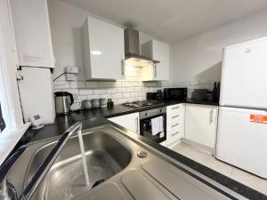 uma cozinha com armários brancos e um lavatório de aço inoxidável em Wenlock Liverpool em Liverpool