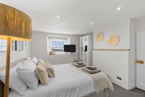 a bedroom with a bed with white sheets and a tv at NEW 2023 Modern Luxury Holiday Home on the Beach in Devon - Free Parking, Pets Welcome, Sleeps 10 in Plymouth