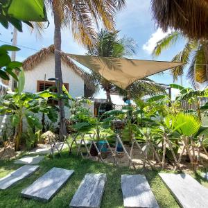 eine Terrasse mit einem Tisch und einem Sonnenschirm und einigen Palmen in der Unterkunft Casa Mandala - Pousada Icaraí Kite Village in Icaraí