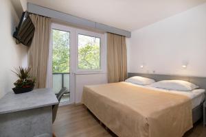 um quarto com uma cama grande e uma janela em Boarding House Lucija em Kostrena