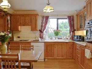 a kitchen with wooden cabinets and a table and a window at The Bungalow in Gristhorpe