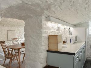 a kitchen with a table and a white wall at Curlew Cottage in Stanhope