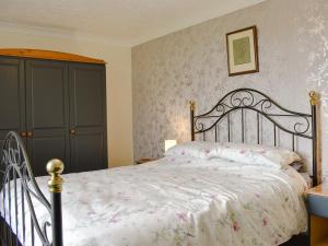a bedroom with a bed with a floral bedspread at Curlew Cottage in Stanhope