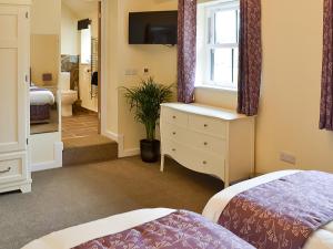 een slaapkamer met 2 bedden en een dressoir met een raam bij The Old Dairy in Ferndown