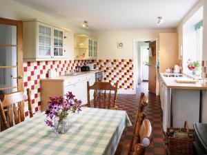 a kitchen with a table with a vase of flowers on it at Coach House in Abbey Dore