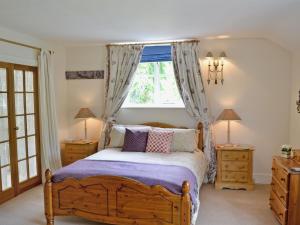 a bedroom with a wooden bed and a window at Coach House in Abbey Dore