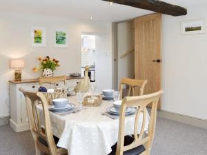 a dining room table with a white table cloth and chairs at Blackcurrant Cottage At Stanton Ford Farm in Baslow