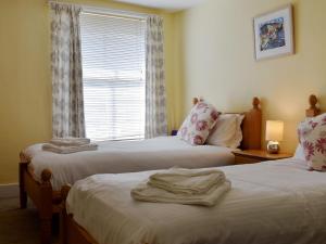 two beds in a room with a window at Old Town Cottage in Sidmouth