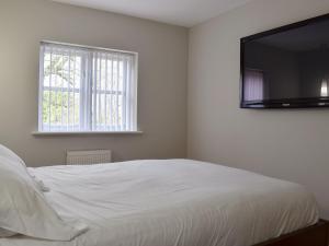 a bedroom with a white bed and a flat screen tv at Hollies Cottage 11 - Ukc4534 in Martock