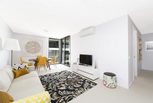 a white living room with a couch and a tv at CityStyle Apartments - BELCONNEN in Canberra