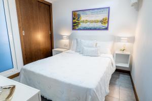 ラ・オロタバにあるEstancia Victoriaの白いベッドと壁に絵画が飾られたベッドルーム1室