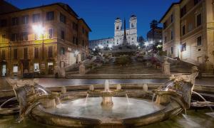 a fountain in the middle of a city with a church at Relais San Lorenzo In Lucina in Rome