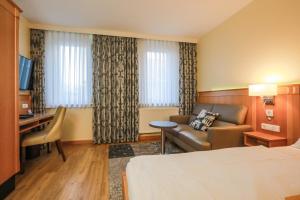 a hotel room with a bed and a couch and a desk at Work & Travel - KRAL Hotels Erlangen in Erlangen