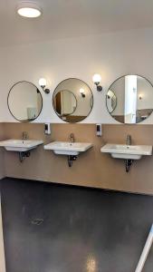 a bathroom with three sinks and two mirrors at Agricampeggio La Part ONLY CAMPER in San Zeno di Montagna