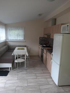 a kitchen with a table and a white refrigerator at Pokoje w lesie in Miłomłyn