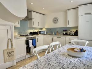a kitchen with white cabinets and a table with chairs at 7 Alfred Square in Deal