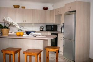 a kitchen with a refrigerator and some wooden stools at Rooikrans Cottage in Great Brak River