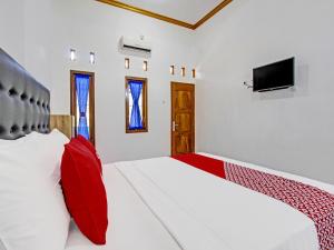 una camera con 2 letti con cuscini rossi e TV di Super OYO 92101 Elma Guesthouse a Yogyakarta