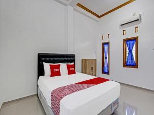 a white bedroom with a large bed with red pillows at Super OYO 92101 Elma Guesthouse in Yogyakarta