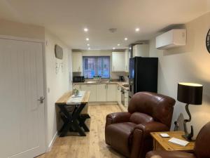 a living room with a chair and a table and a kitchen at Pet Friendly Cottage Ashbourne with Parking in Ashbourne