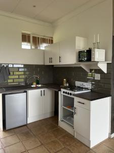 een keuken met witte kasten en een fornuis met oven bij Dewdrop Farm Stay in Ermelo