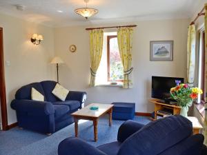 a living room with blue chairs and a tv at Anvil in Dalbeattie