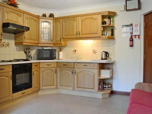 a kitchen with wooden cabinets and a microwave at Anvil in Dalbeattie