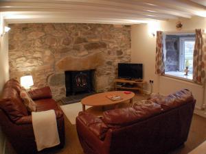 a living room with leather furniture and a stone fireplace at Tigh Nan Eoin in Aultbea