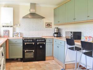 a kitchen with a black stove and blue cabinets at Longtye Cottage in Swalecliffe