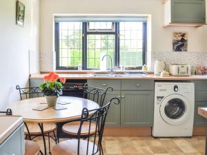 a kitchen with a table and a washing machine at Longtye Cottage in Swalecliffe