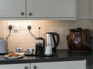a kitchen counter with a coffee maker and a plate of cookies at The Old Rectory Cottage in Great Carlton