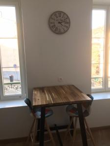 uma mesa com duas cadeiras e um relógio na parede em Le Montgy - Studio tout confort à Royat National N1 em Royat