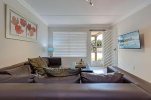 a living room with a brown leather couch at RAD STAYS - 26 Madison Palms East 112 North Road Sandown in Johannesburg