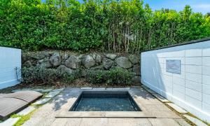 a swimming pool in the ground next to a stone wall at Pool and Villa Sorang in Jeju