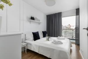 a white bedroom with a bed and a window at Navigator Portowa Residence Kołobrzeg Apartment by Renters in Kołobrzeg